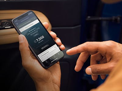 Person using a smartphone app inside a car, displaying a screen with 7,500 reward points available.